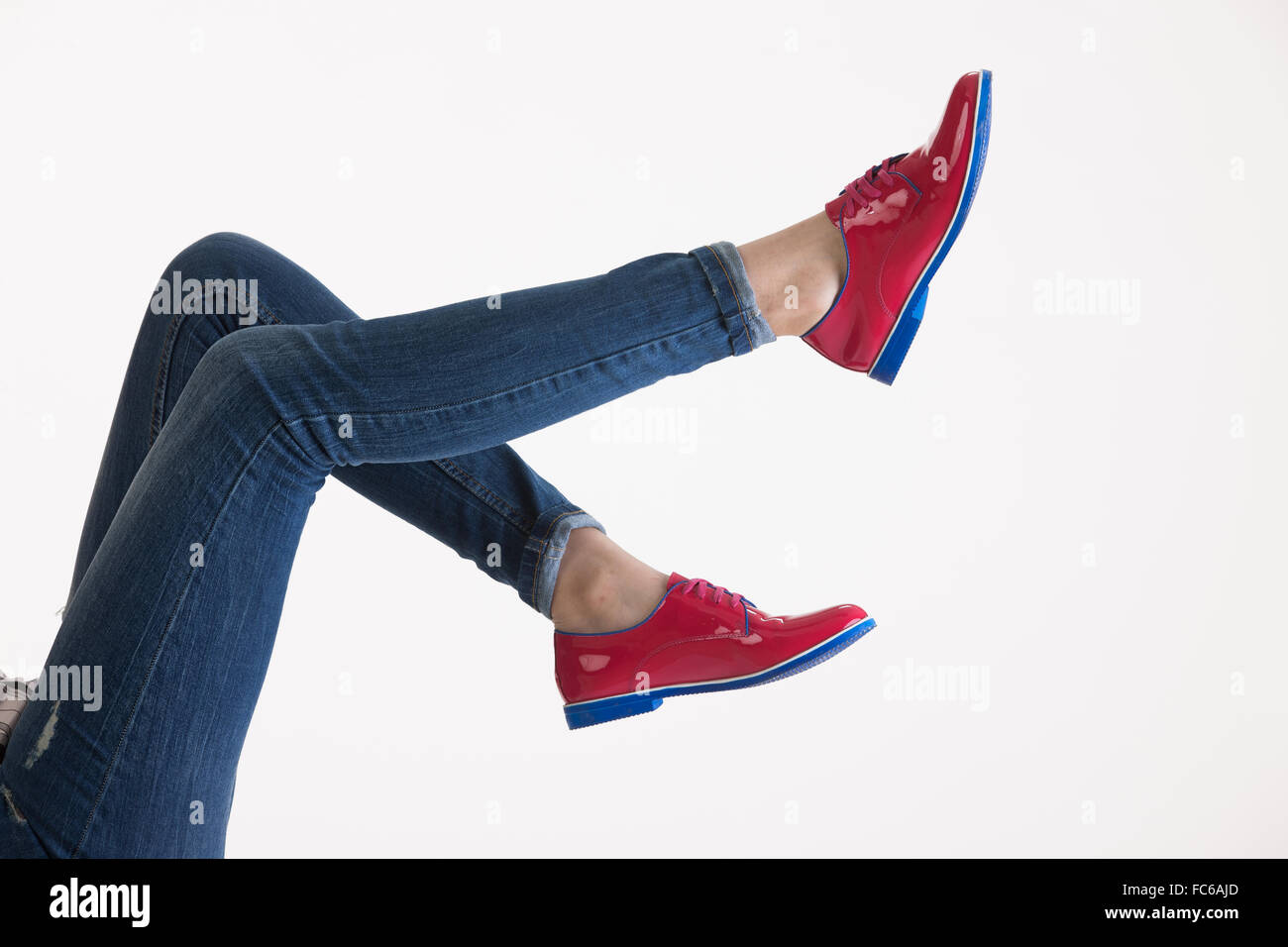 La donna per le gambe in blue jeans e scarpe rosso Foto Stock