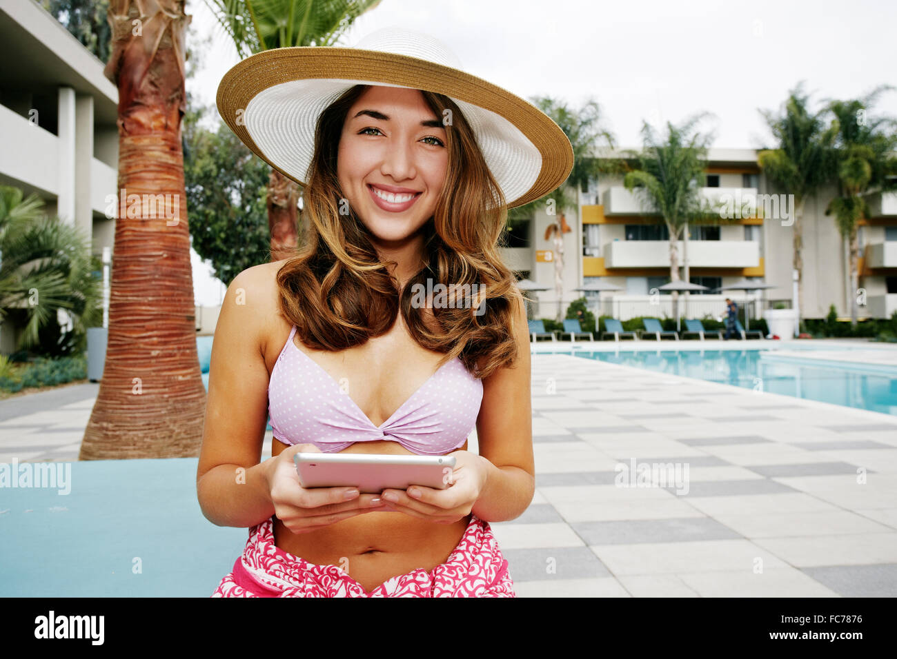 Donna ispanica con tavoletta digitale in piscina Foto Stock