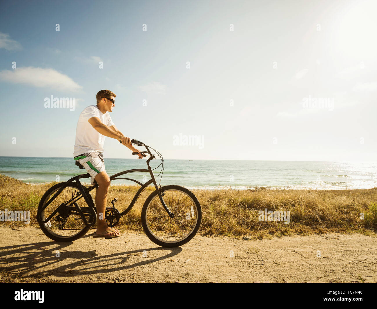 Uomo caucasico Bicicletta Equitazione sulla spiaggia Foto Stock