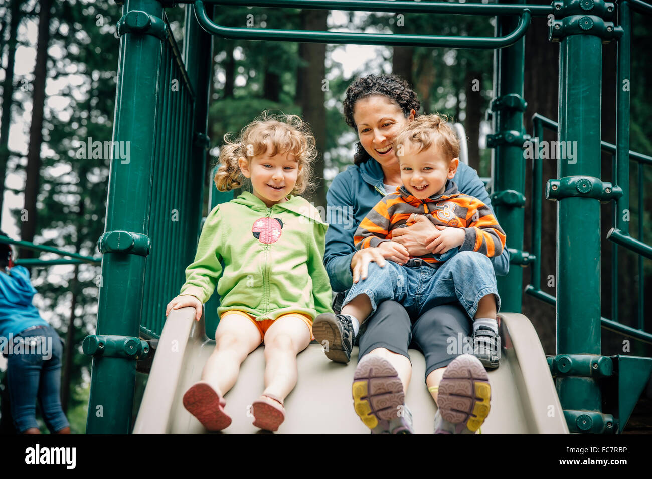 Caucasian madre e bambini che giocano sul parco giochi Foto Stock