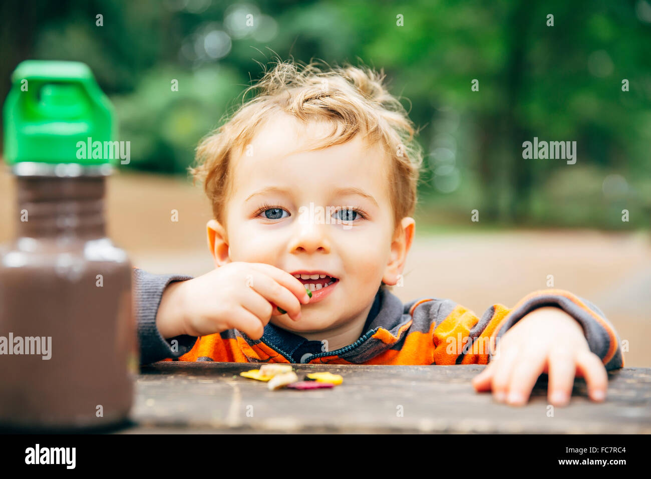 Ragazzo caucasico mangiando snack al tavolo da picnic Foto Stock