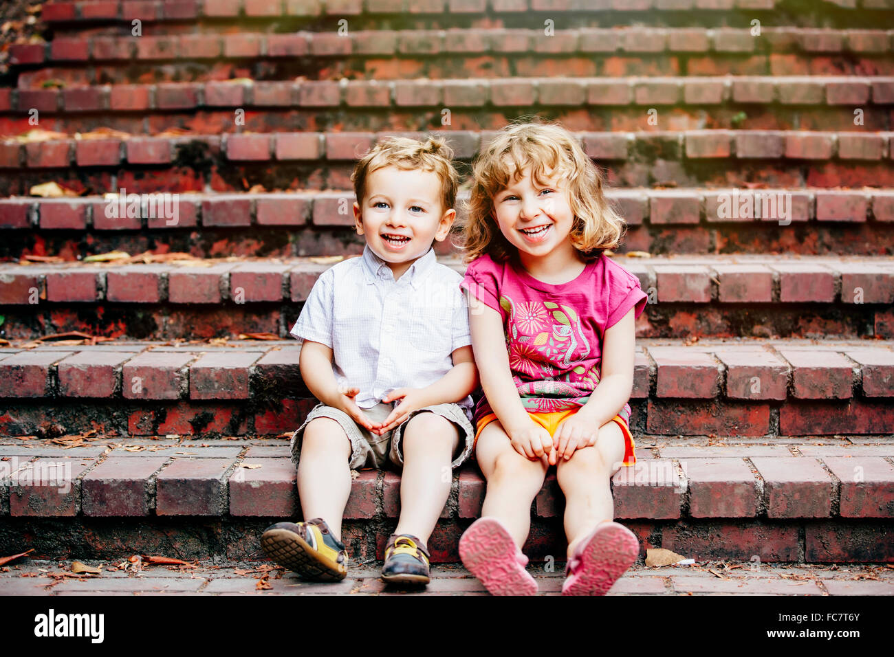 Caucasian bambini seduti sui gradini Foto Stock