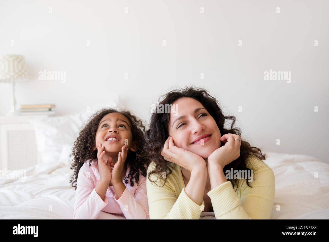 Madre e figlia fantasticando su letto Foto Stock