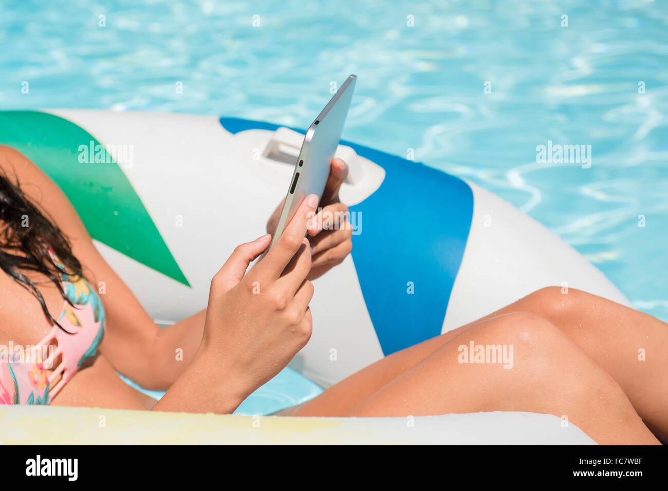 La donna caucasica utilizzando digitale compressa in piscina Foto Stock