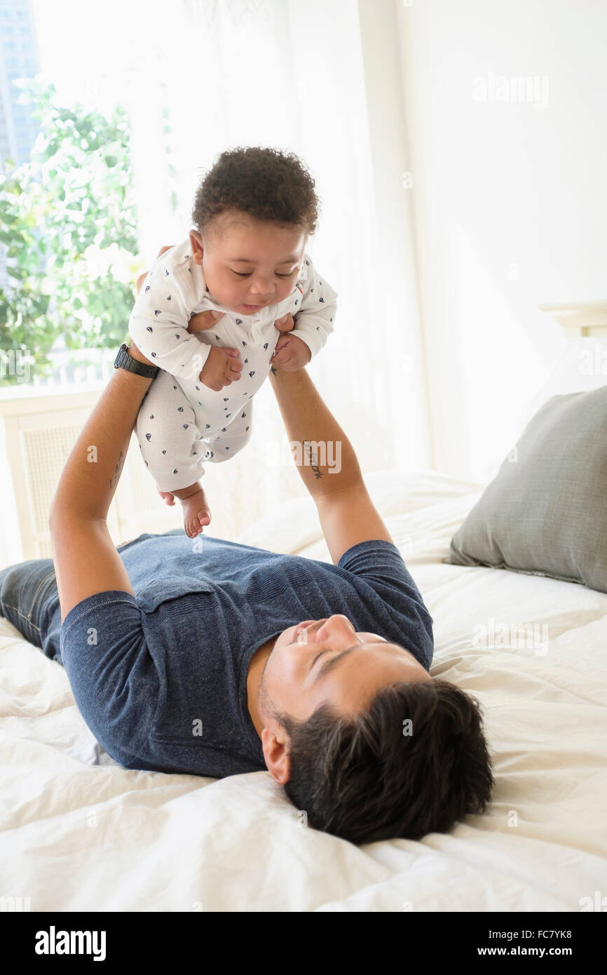 Padre holding baby figlio sul letto Foto Stock