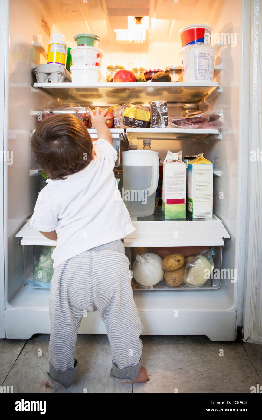 Razza mista baby boy esplorare frigorifero Foto Stock