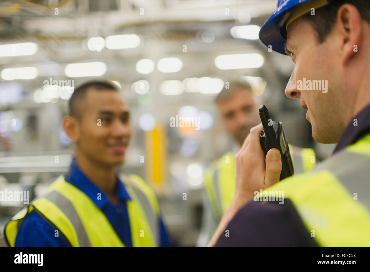 Lavoratore utilizzando un walkie-talkie in fabbrica Foto Stock