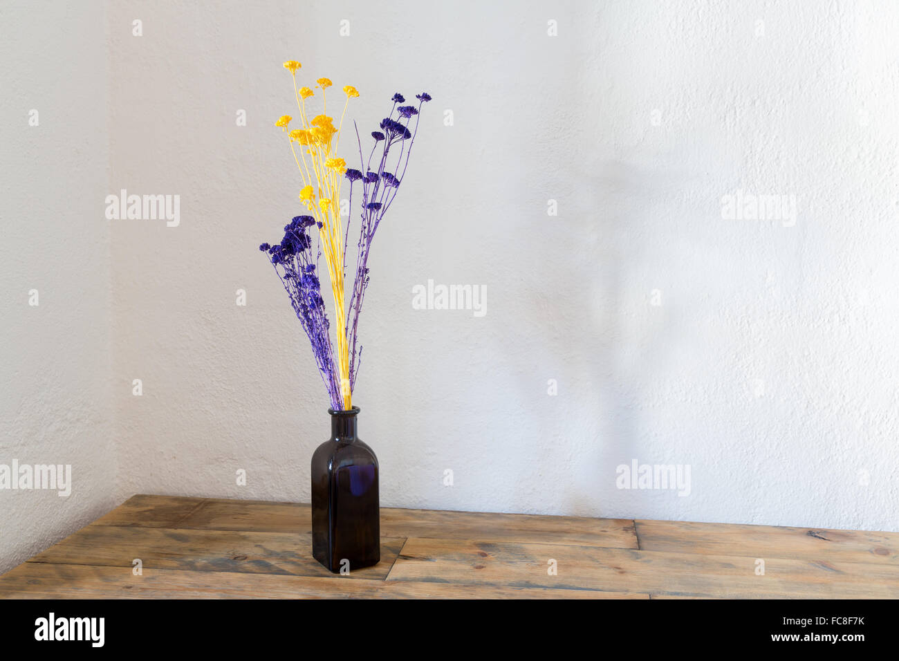 Fiori Secchi in bottiglia blu vaso su legno Foto Stock
