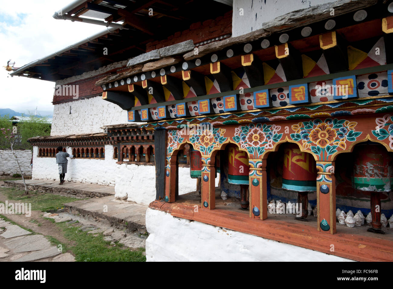 Buddista uomo tempio di filatura ruote della preghiera al di fuori Dumtse Lakhang tempio buddista, Bhutan Foto Stock
