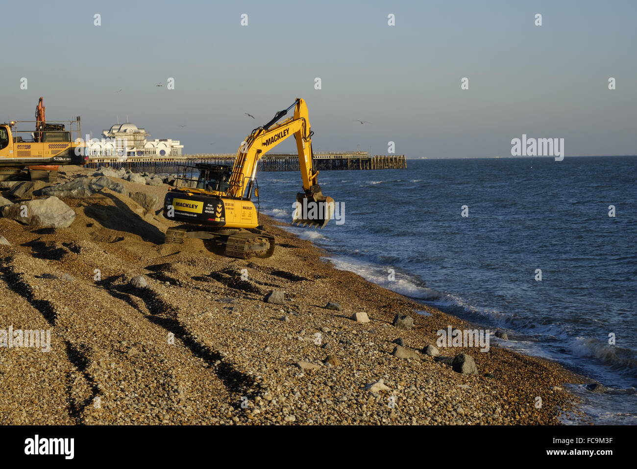 Impianto di pesanti macchinari immissione massi per la riparazione di tempesta danneggiato promenade a Southsea England Regno Unito Foto Stock