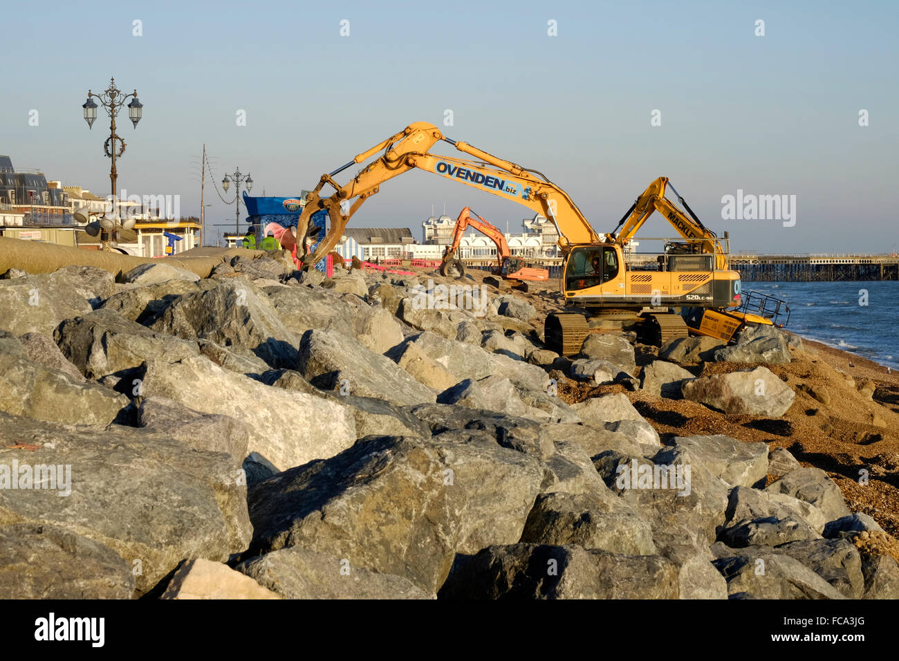 Impianto di pesanti macchinari immissione massi per la riparazione di tempesta danneggiato promenade a Southsea England Regno Unito Foto Stock