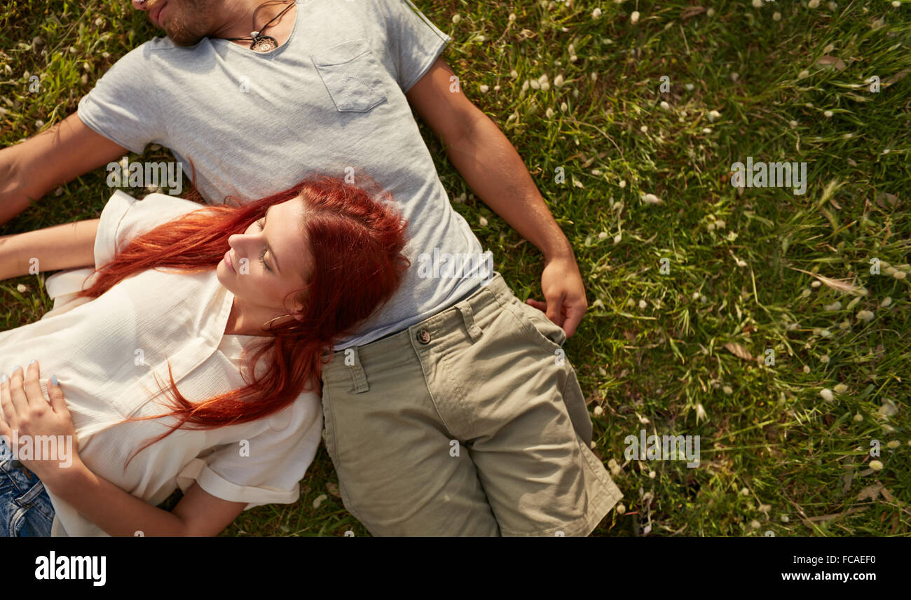 Giovane donna sdraiata sul prato con il suo fidanzato. Vista aerea della coppia giovane rilassante sull'erba, con copia spazio. Foto Stock