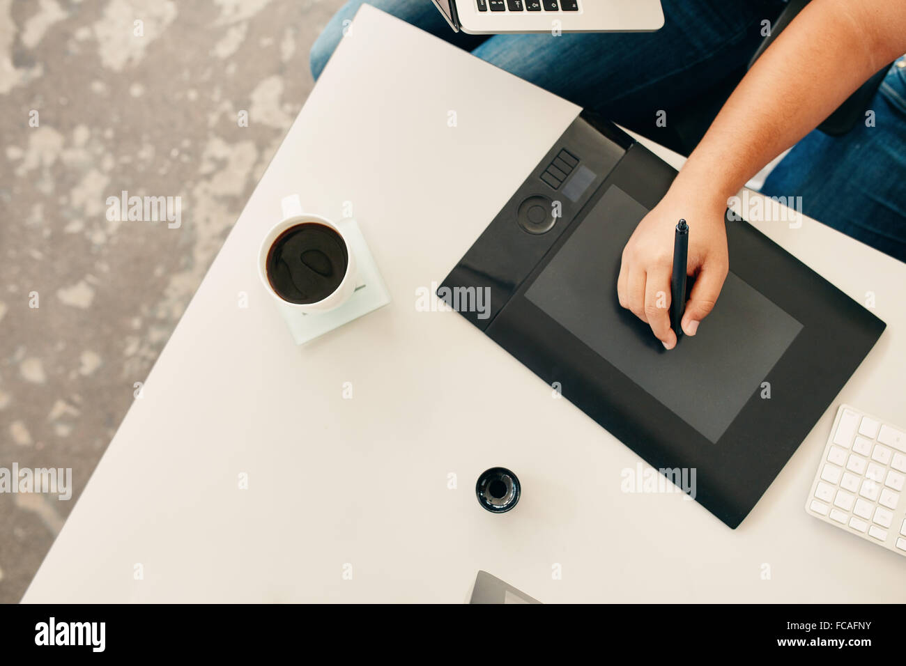 Vista superiore dell'artista maschile mano utilizzando una tavoletta digitale e penna stilo. Foto retoucher lavorando alla sua scrivania con una tazza di caffè. Foto Stock