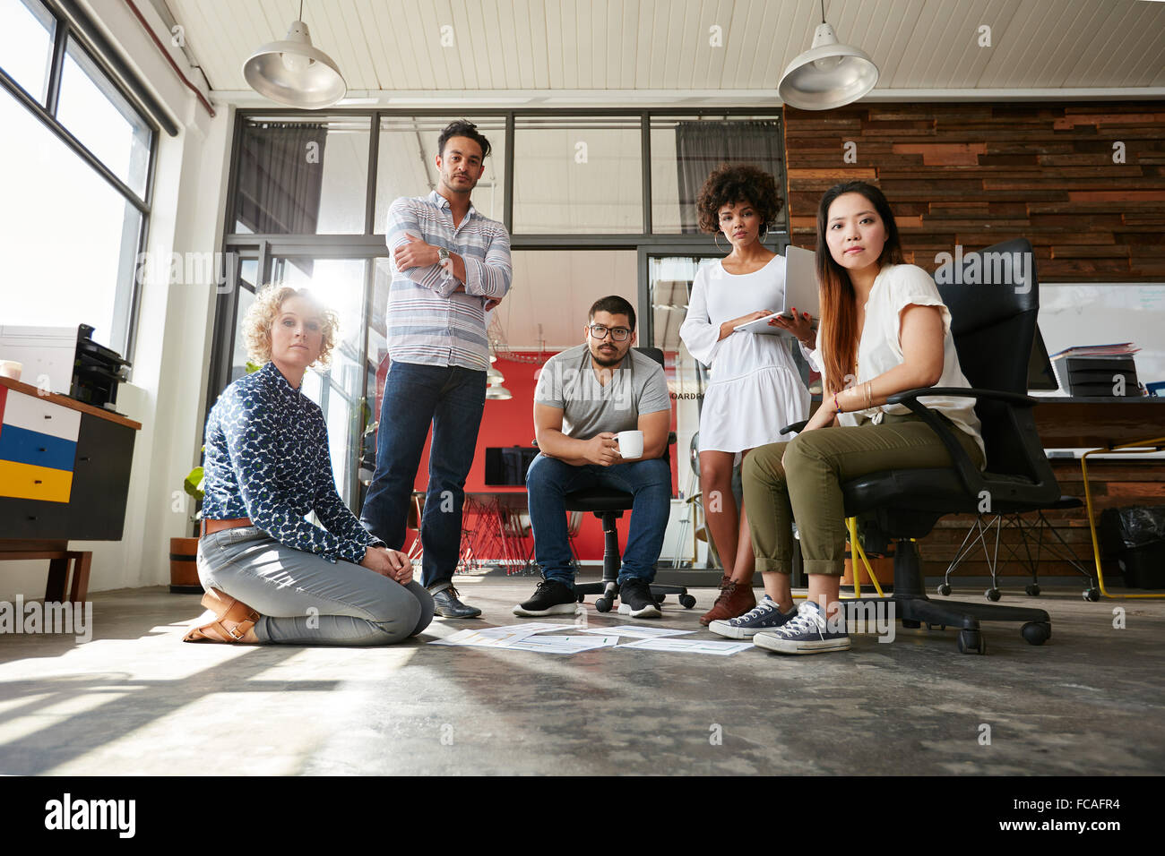 Ritratto di team creativi insieme guardando la fotocamera. I giovani designer di riunione per la finalizzazione di un layout di progetto. Foto Stock