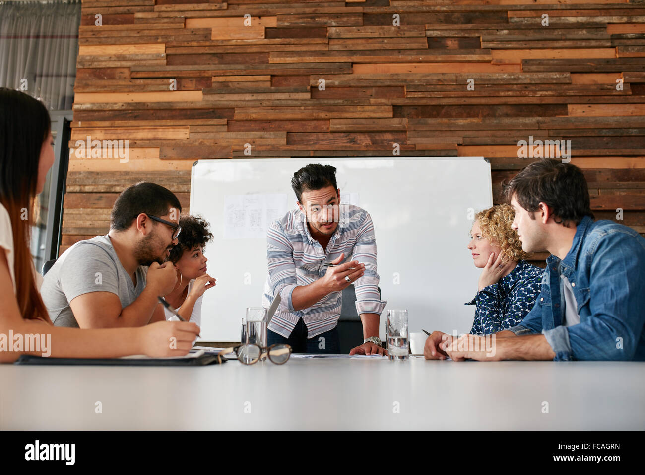 Il brainstorming in una sala riunioni di creative office . Giovani creativi seduta al tavolo e discutere di nuovi progetti. Foto Stock
