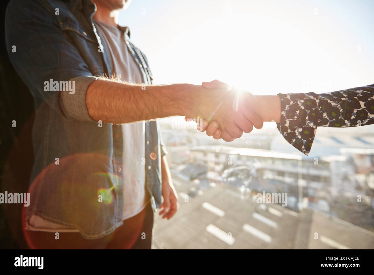 Primo piano della stringe la mano di un uomo e di una donna con lens flare. Focus sulla stretta di mano in una giornata di sole. Foto Stock