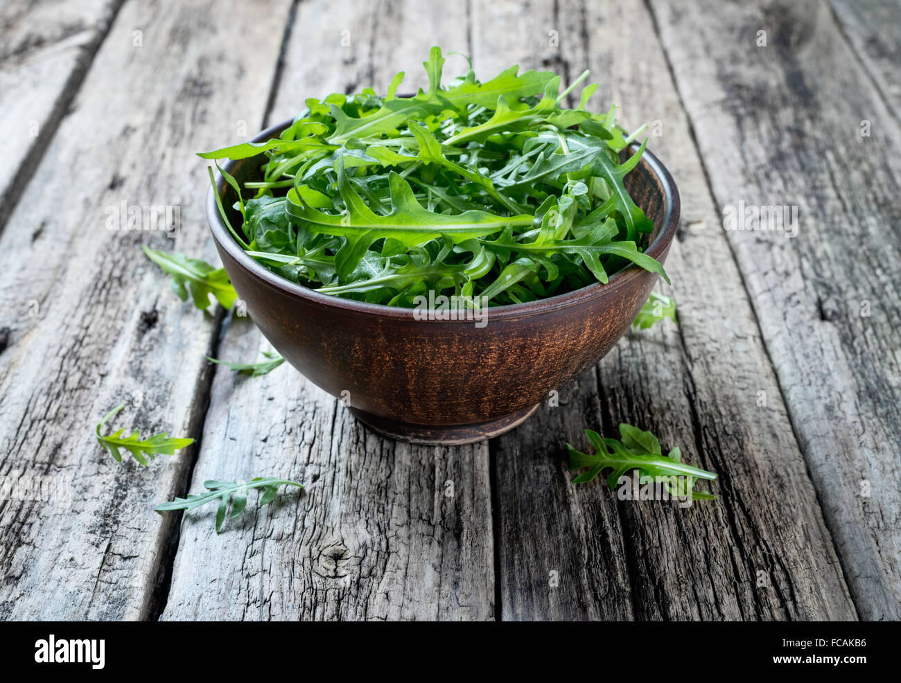 Rucola fresca in una ciotola su una tavola in legno rustico. Foto Stock