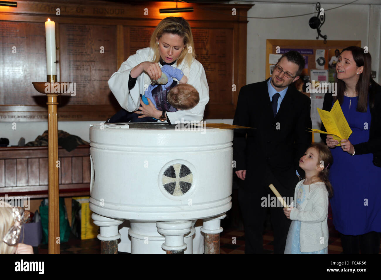 Battesimo presso la chiesa di Saint Mary Caterham sulla collina Surrey in Inghilterra sacerdote femmina versando acqua santa sul Baby Boy utilizzando Shell Foto Stock