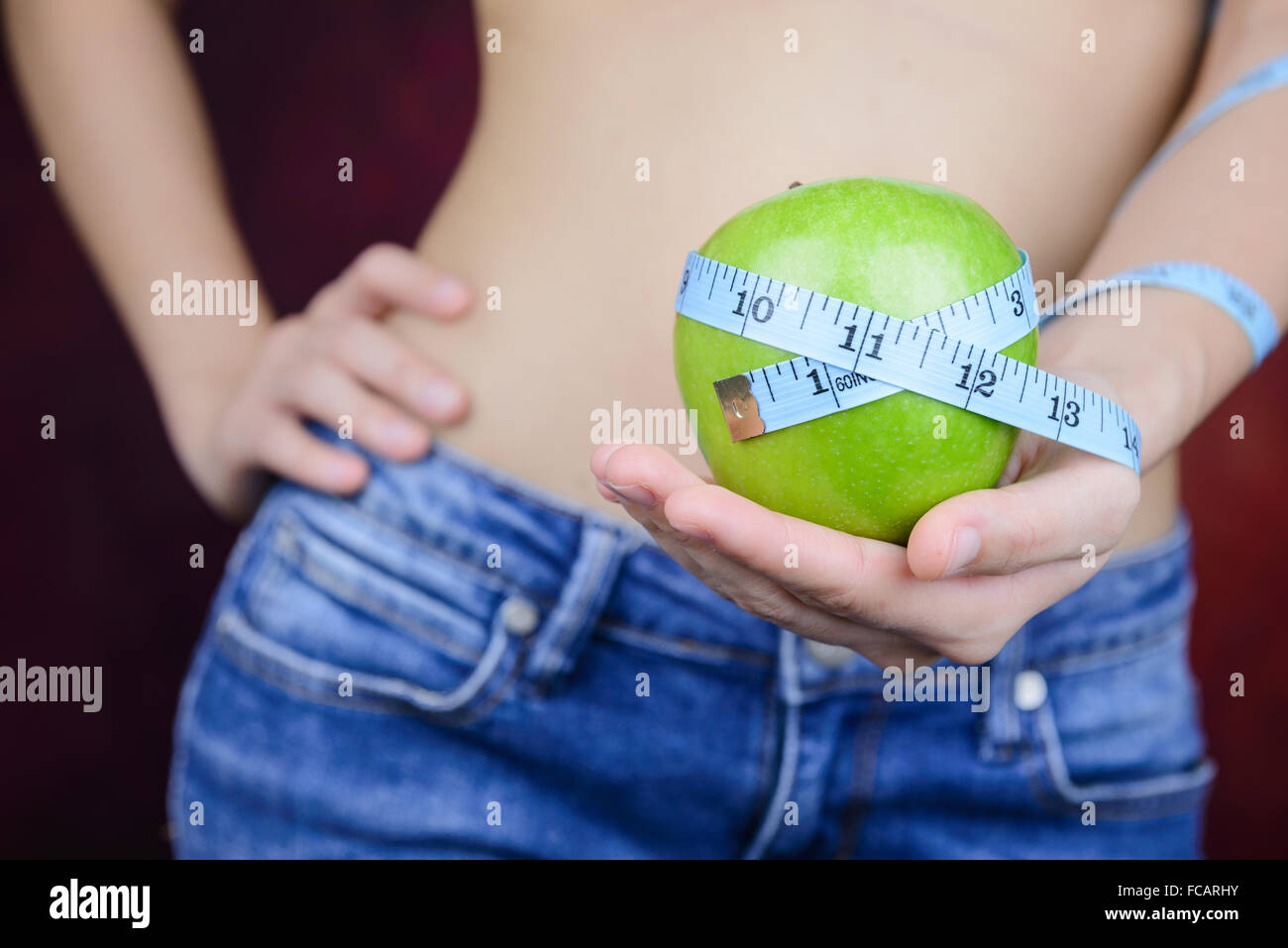 Slim donna asiatica , indossano jeans, porta di mela verde e nastro di misurazione in mano Foto Stock