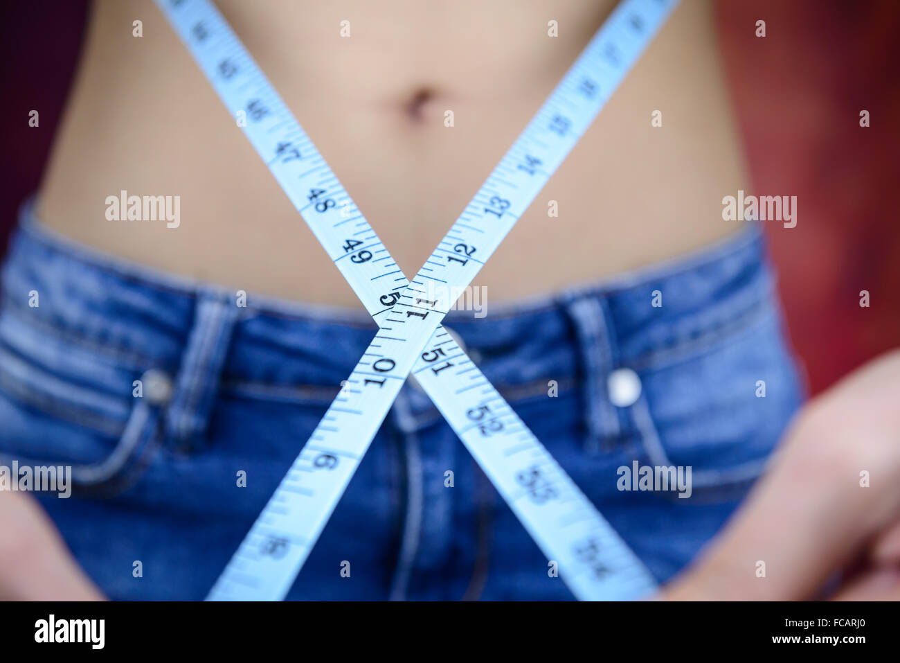 Slim donna asiatica , indossano jeans, misurando la sua forma del corpo, alla cintura, glutei Foto Stock