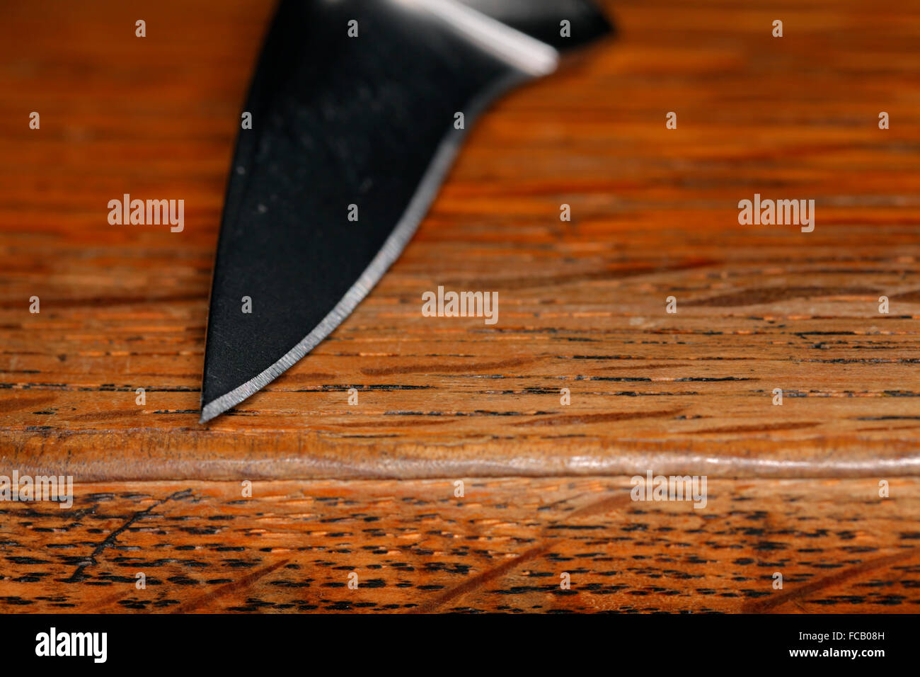 La lama di un coltello sulla superficie di legno. Foto Stock