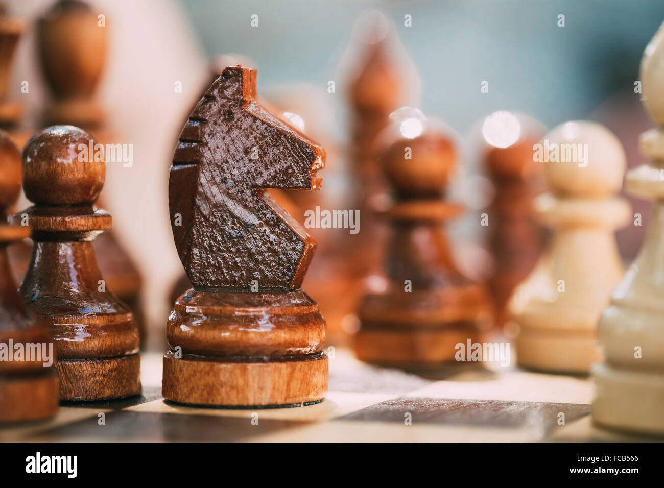 Vecchio Scacchi marrone cavaliere e pegni permanente sulla scacchiera in legno Foto Stock