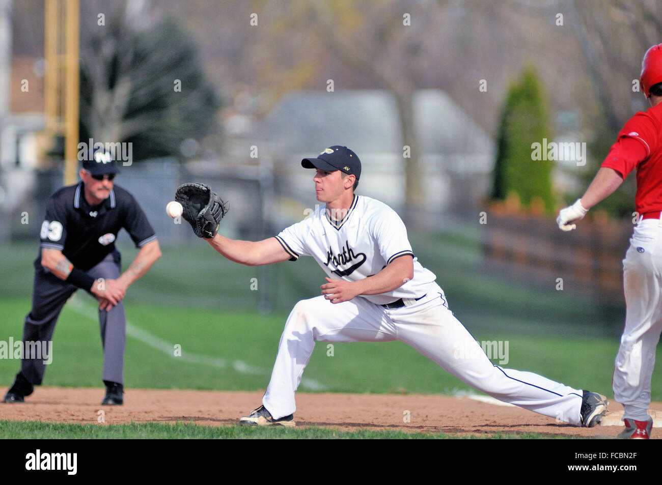 Alta scuola primo baseman accettando un tiro alla prima base al ritiro un hitter di opposti che aveva colpito una palla di massa al infield. Stati Uniti d'America. Foto Stock