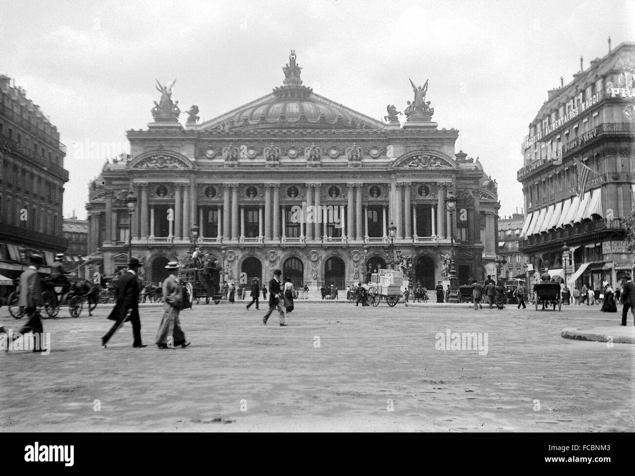 AJAXNETPHOTO. 1900. PARIGI, FRANCIA. - PALAIS GARNIER - PEDONI CHE ATTRAVERSANO LA PIAZZA DI FRONTE ALL'OPERA - L'OPERA - NEI GIORNI DI TRAFFICO TRAINATO DA CAVALLI E RAGAZZI DI CORVO. FOTO:AJAX LIBRERIA DI IMMAGINI VINTAGE RIF: PARIS L'OPERA 1900 Foto Stock