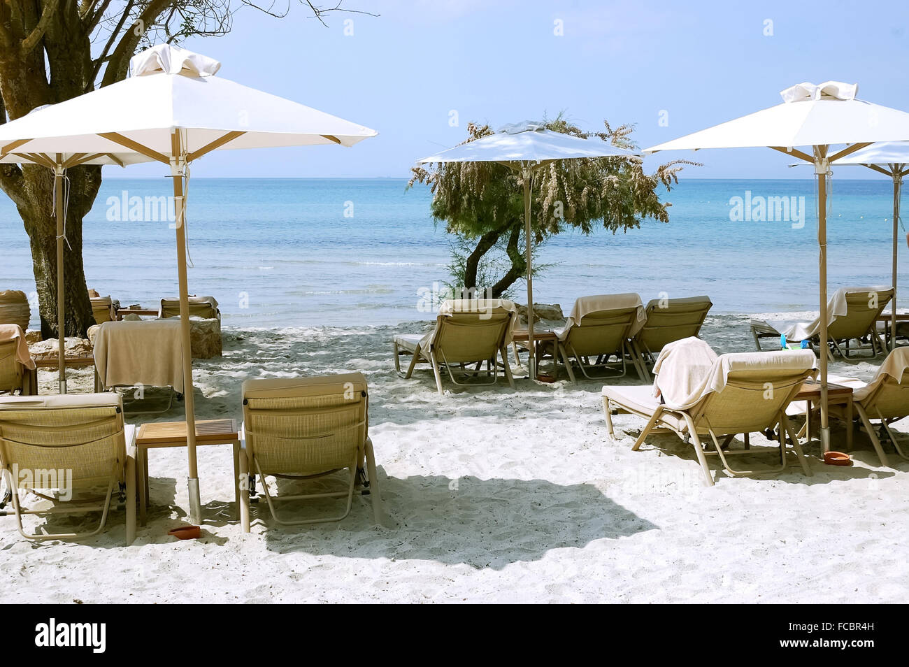 Bianchi ombrelloni e lettini sulla spiaggia in Grecia. Foto Stock