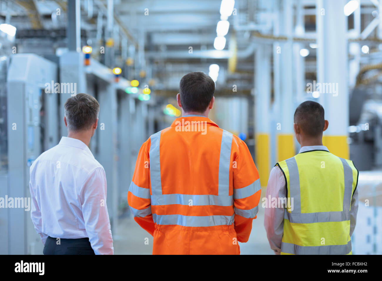 Lavoratori e supervisore in piedi nel corridoio di fabbrica Foto Stock