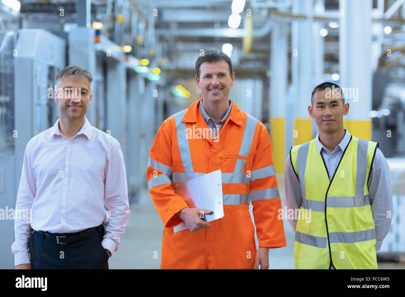 Ritratto di lavoratori sorridente in abiti riflettenti in fabbrica Foto Stock