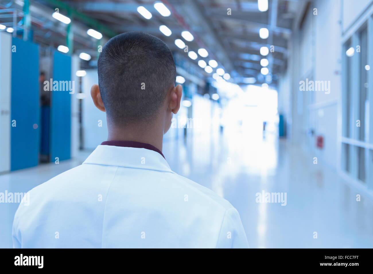 Scienziato guardando verso il basso lungo il corridoio di fabbrica Foto Stock