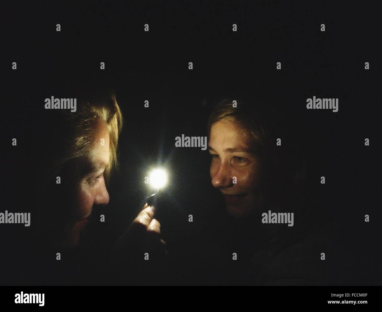 Sorridente due giovani donne con luce nel buio Foto Stock