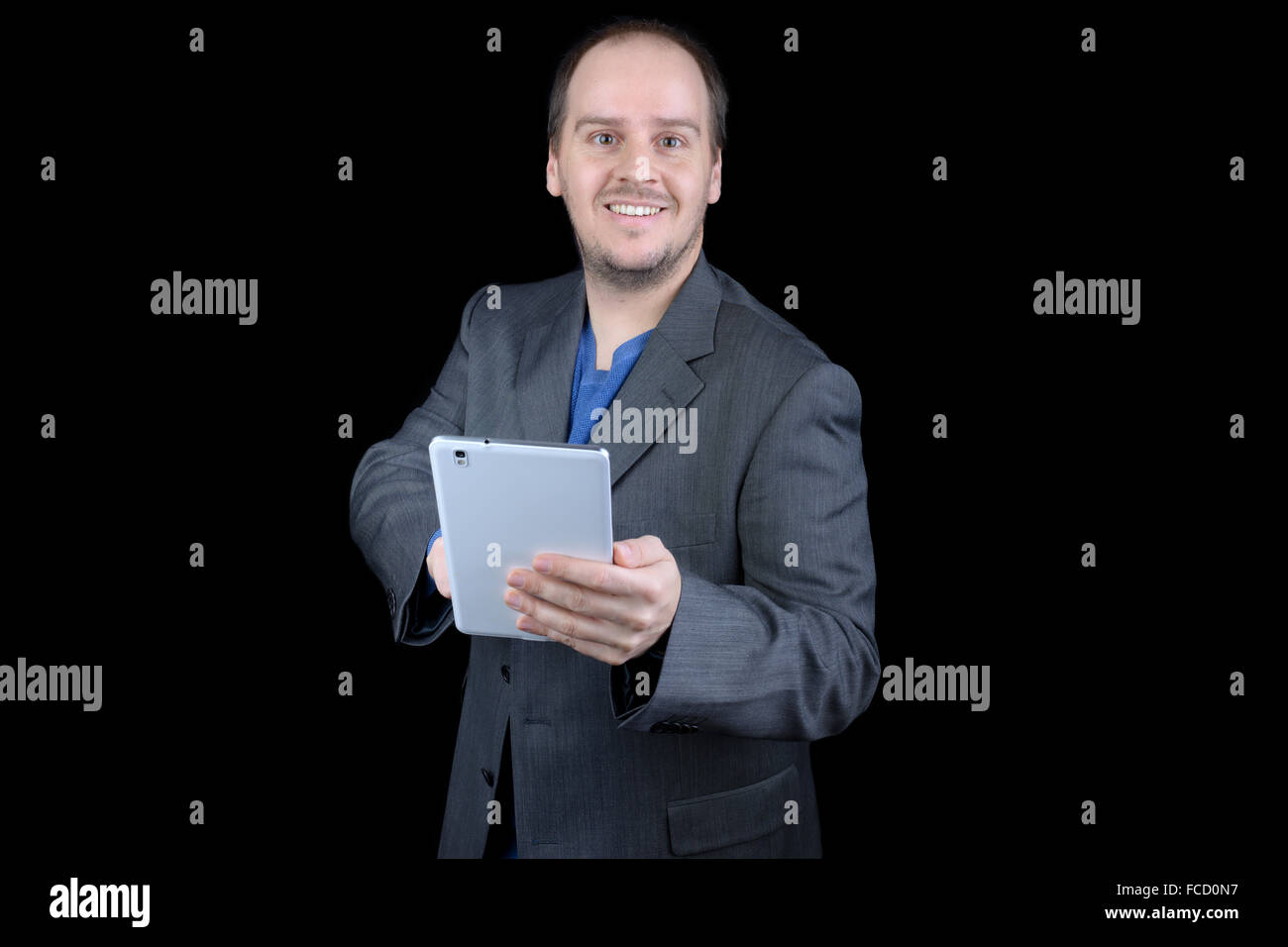 Giovane uomo grigio scuro suit sorridente compressa di puntamento Foto Stock