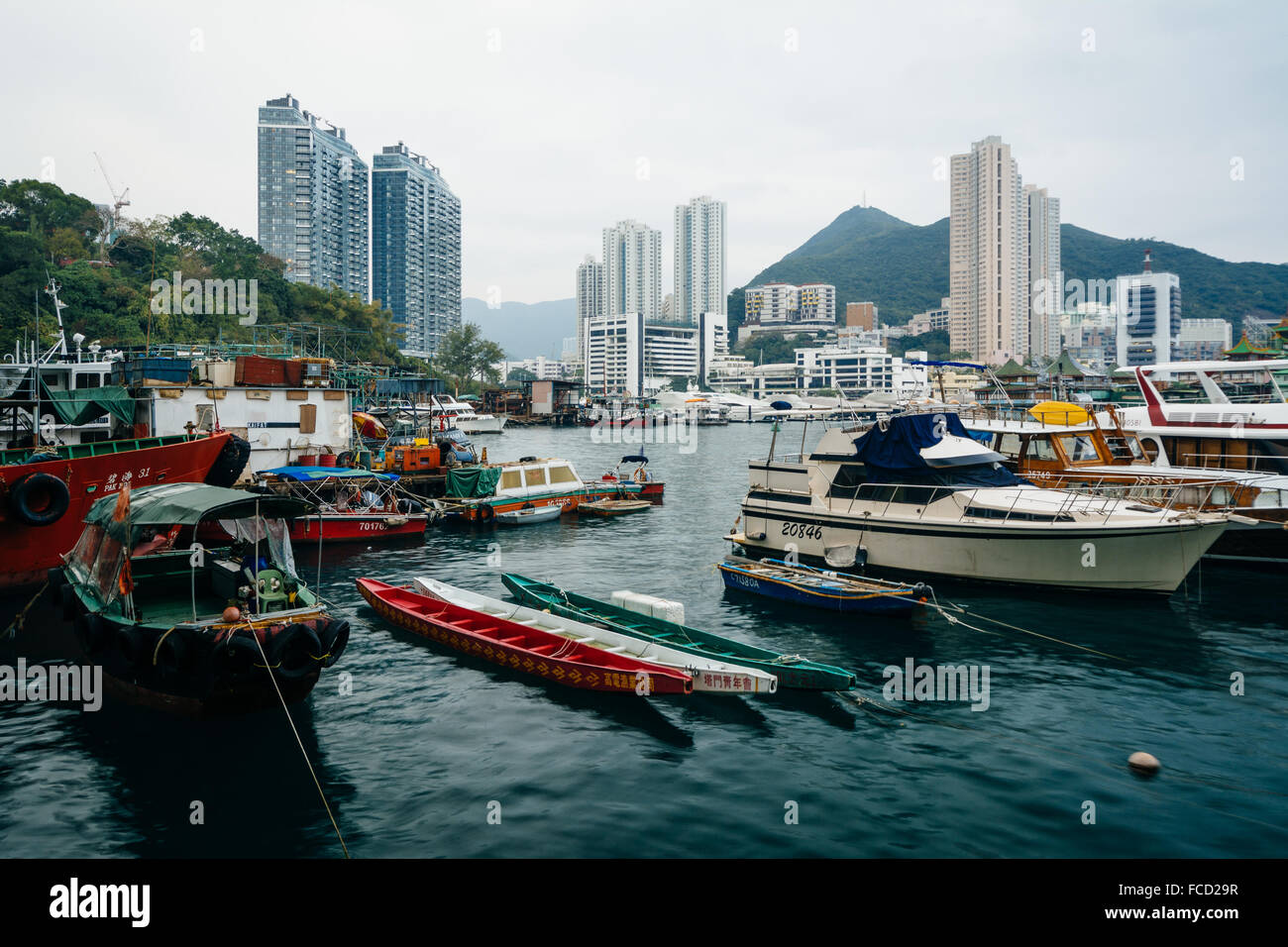 Barche ormeggiate a Ap Lei Chau e vista dei grattacieli e montagne di Hong Kong, Hong Kong. Foto Stock