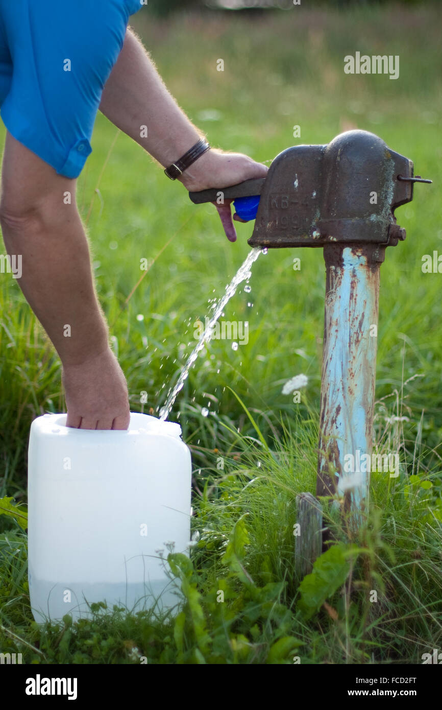 Un uomo raccoglie l'acqua dalla vecchia pompa acqua Foto Stock