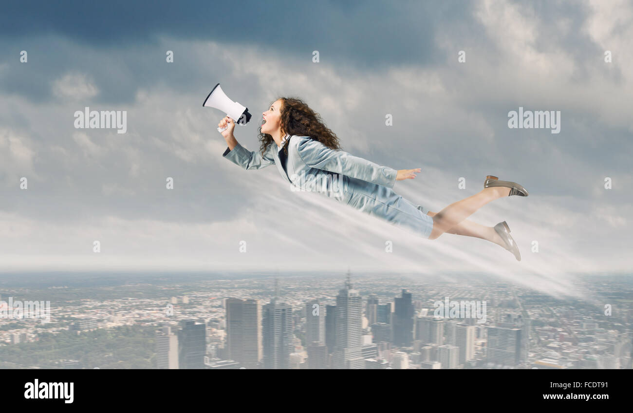 Giovane imprenditrice con megafono volare alto nel cielo Foto Stock