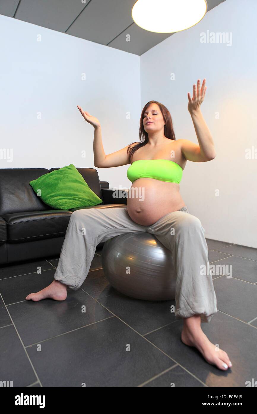 Francia, incinta giovane donna facendo esercizi yoga sul palloncino gonfiabile Foto Stock