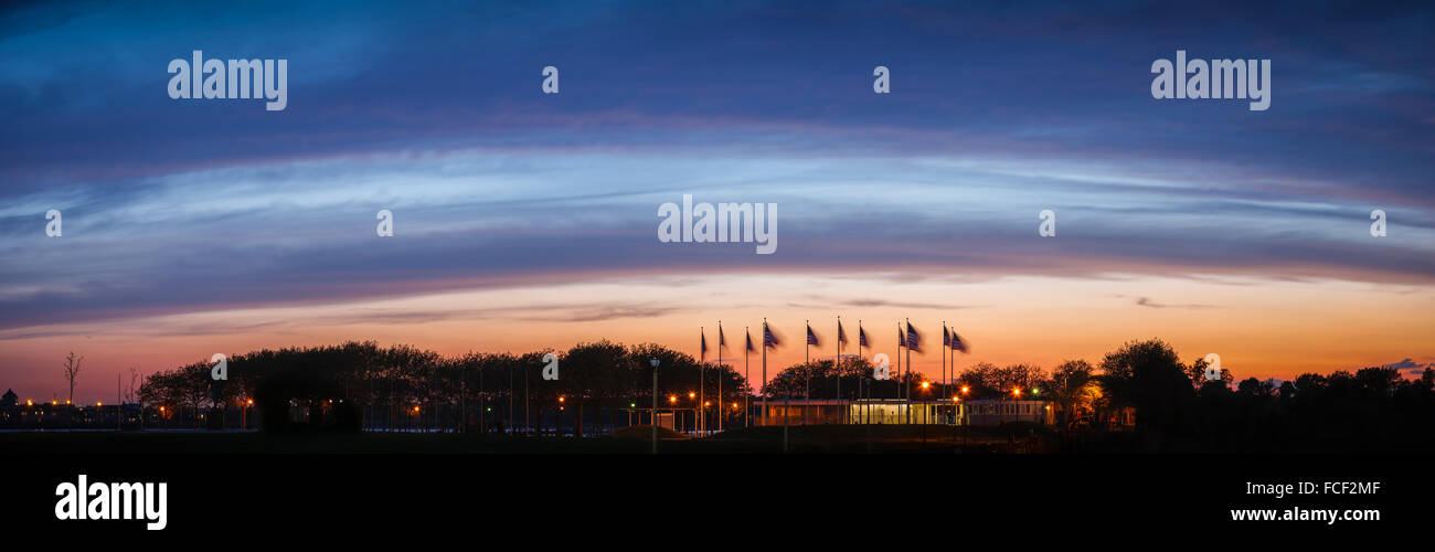 Bandiera Plaza's American banner sbattimenti nel vento contro uno sfondo di deep blue clouds al tramonto vicino a Jersey City, NJ. Foto Stock