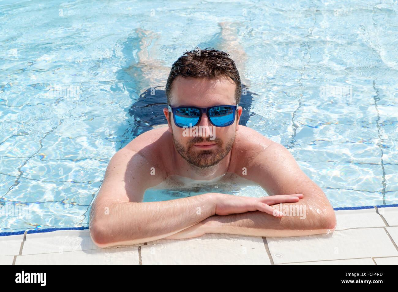 Un uomo con occhiali da sole rilassante in piscina Foto stock - Alamy