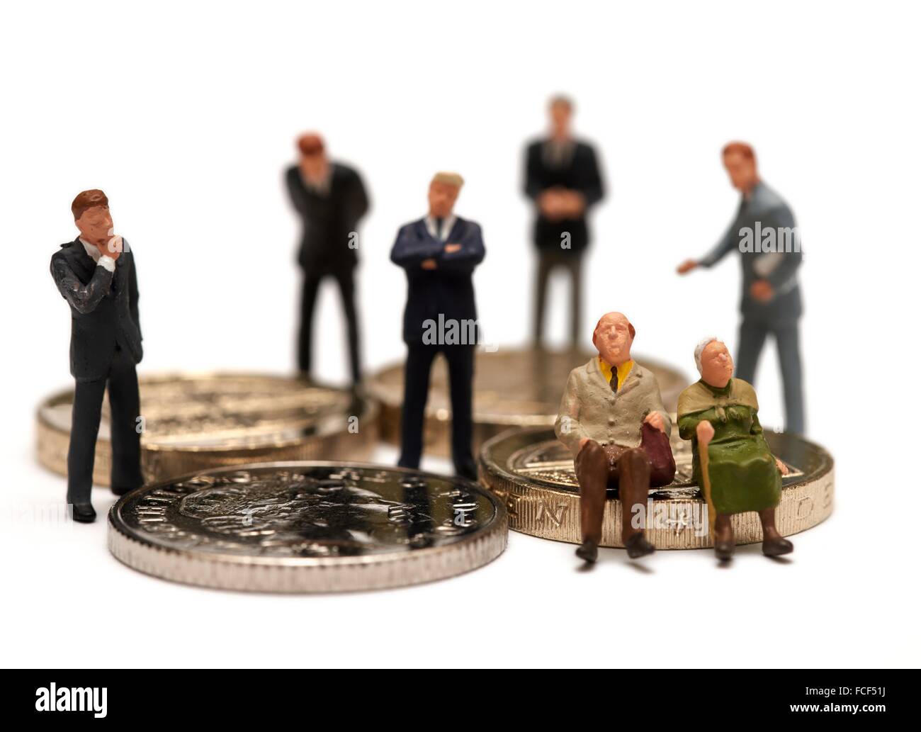 Una miniatura del titolare di pensione o di rendita giovane seduto sulle monete Britanniche circondato da advisor finanziario di tute concetto. Foto Stock
