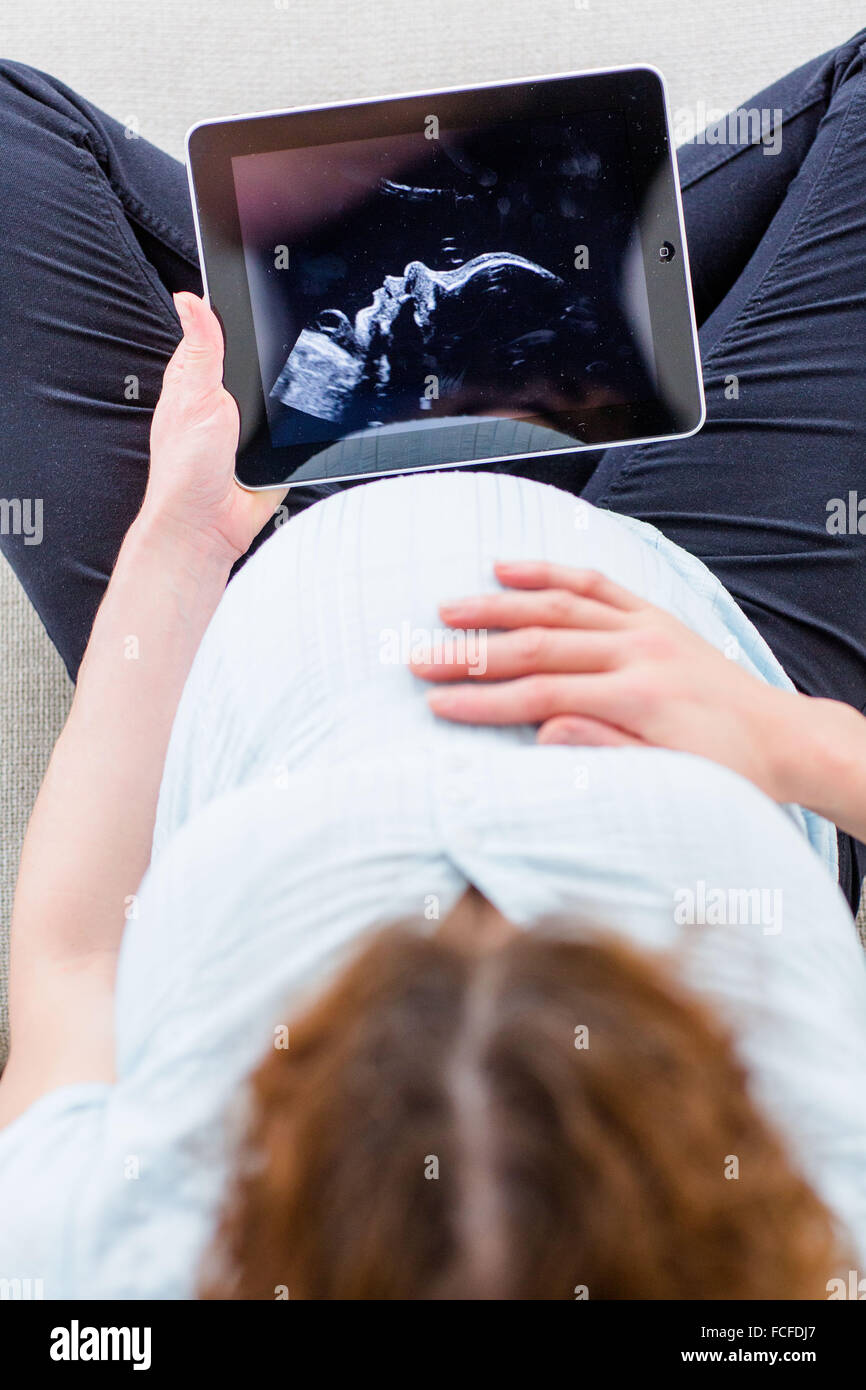 Donna che guarda la baby scan su una tavoletta digitale. Foto Stock