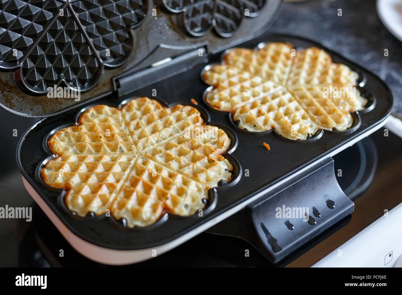 Due waffles fatti in casa su elettrico cialdiera ferro sulla sommità della stufa in cucina Foto Stock