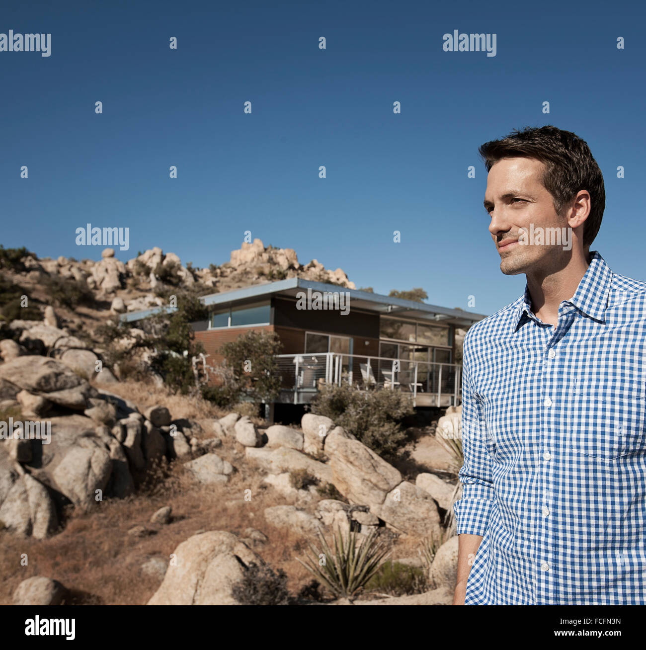Un uomo in piedi di fronte a una casa ecologica e sostenibile di architettura con un basso impatto. Foto Stock