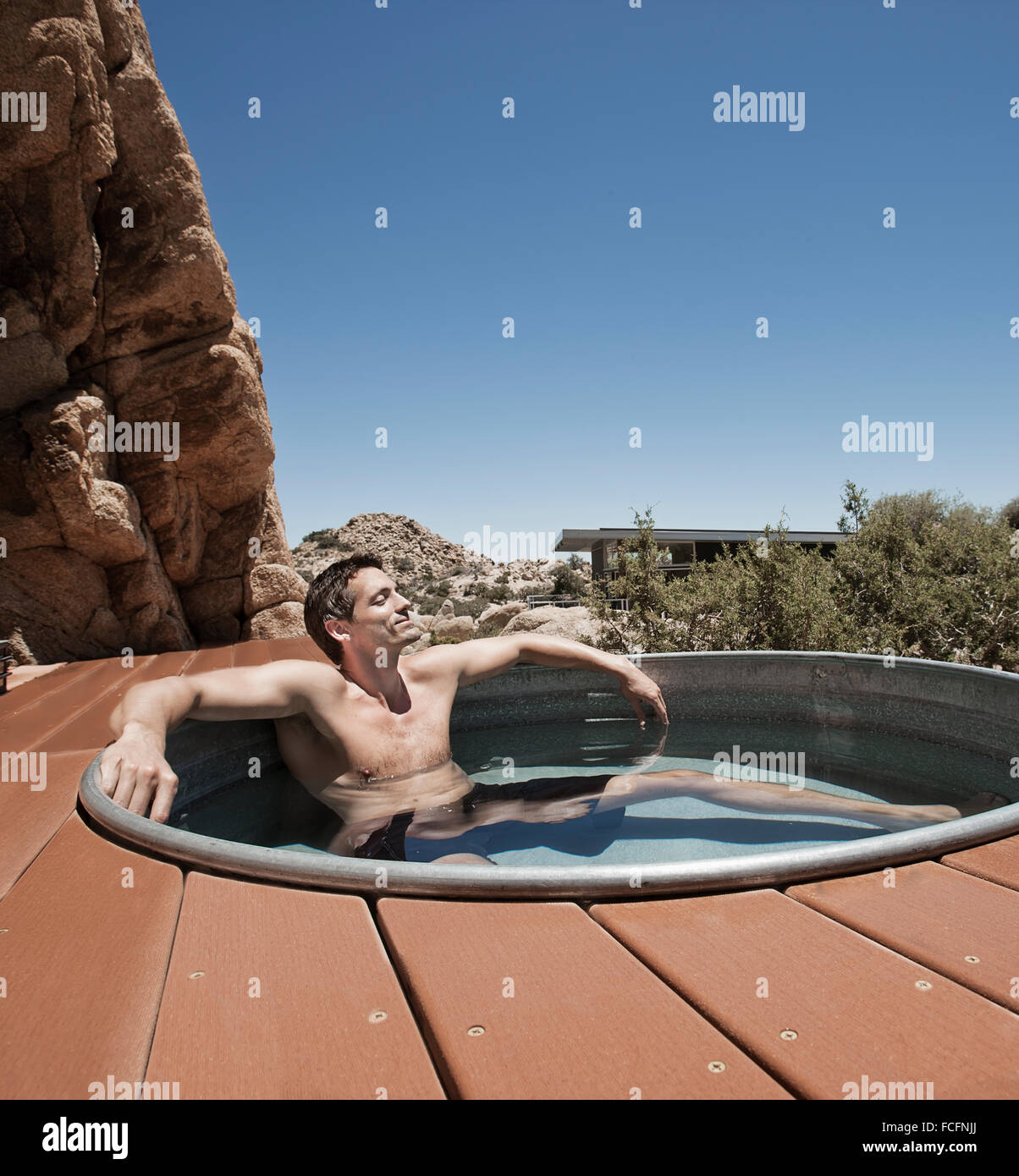 Un uomo sulla terrazza di un eco home, un basso impatto casa nel paesaggio del deserto in un relitto vasca calda. Foto Stock