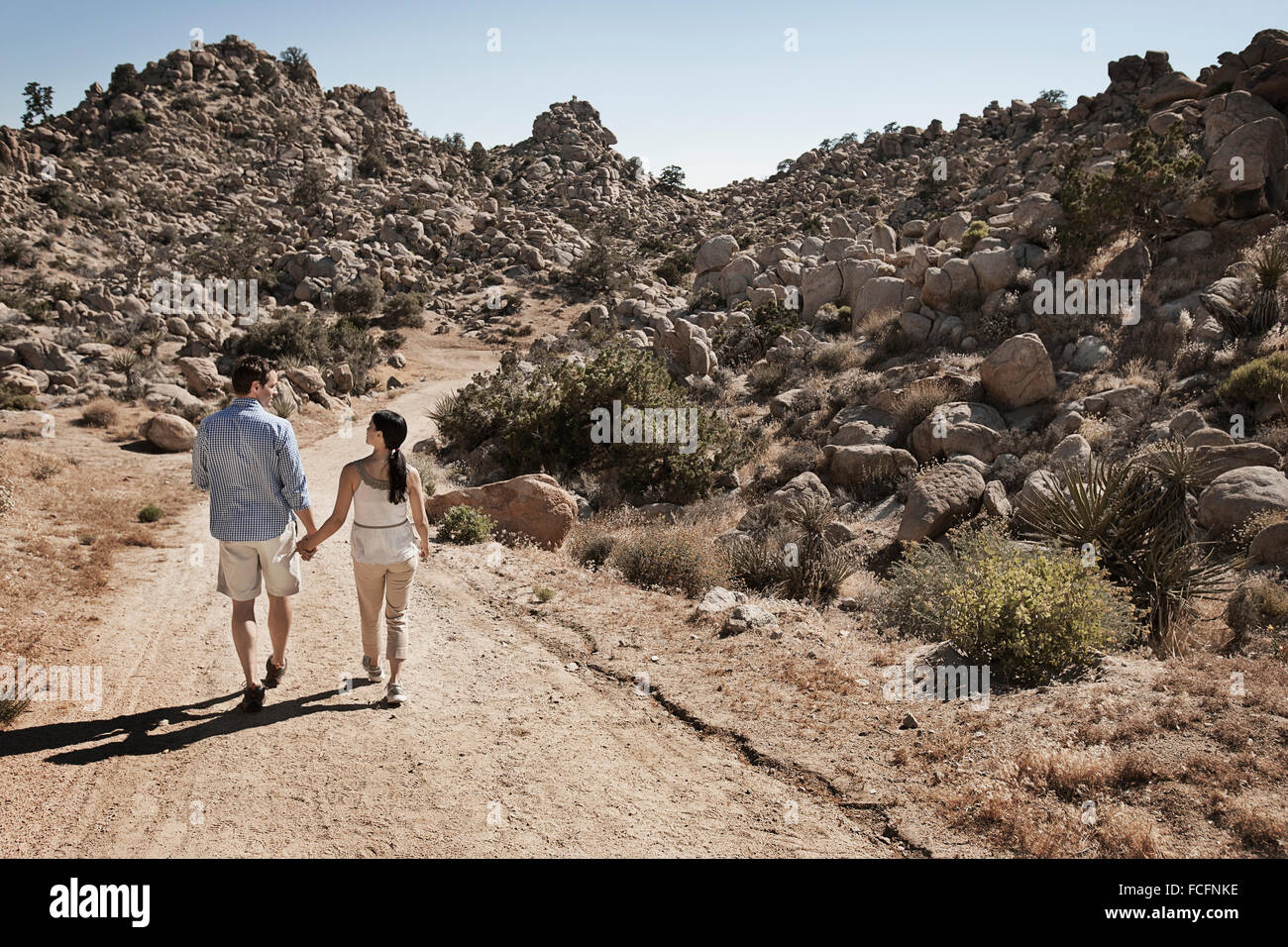 Due persone, una giovane a piedi attraverso un paesaggio roccioso lungo un percorso. Foto Stock