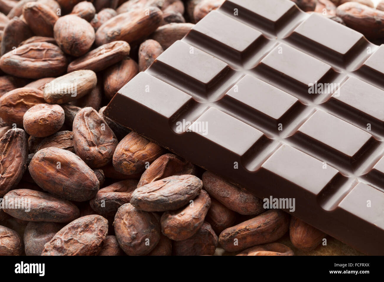 Barretta di cioccolato con materie prime fave di cacao Foto Stock