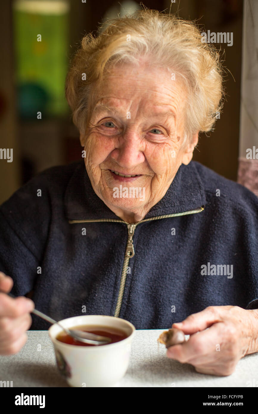Donna anziana bere il tè in cucina. Foto Stock