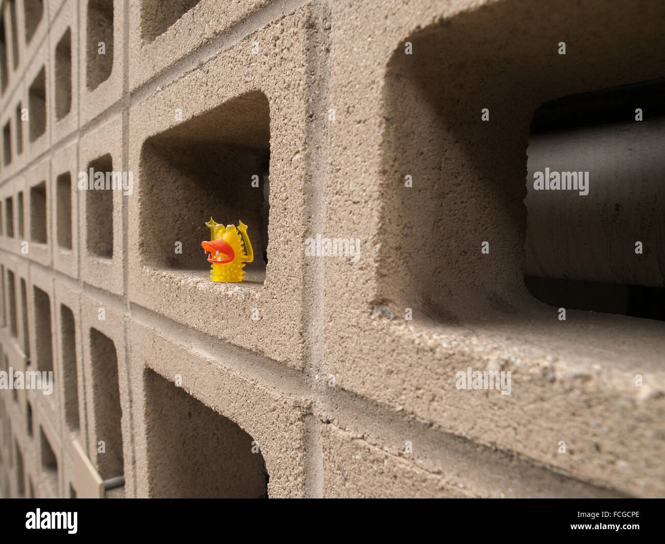 Parete di blocchi di calcestruzzo di scorie e piccolo giallo monster dito fantoccio. Foto Stock