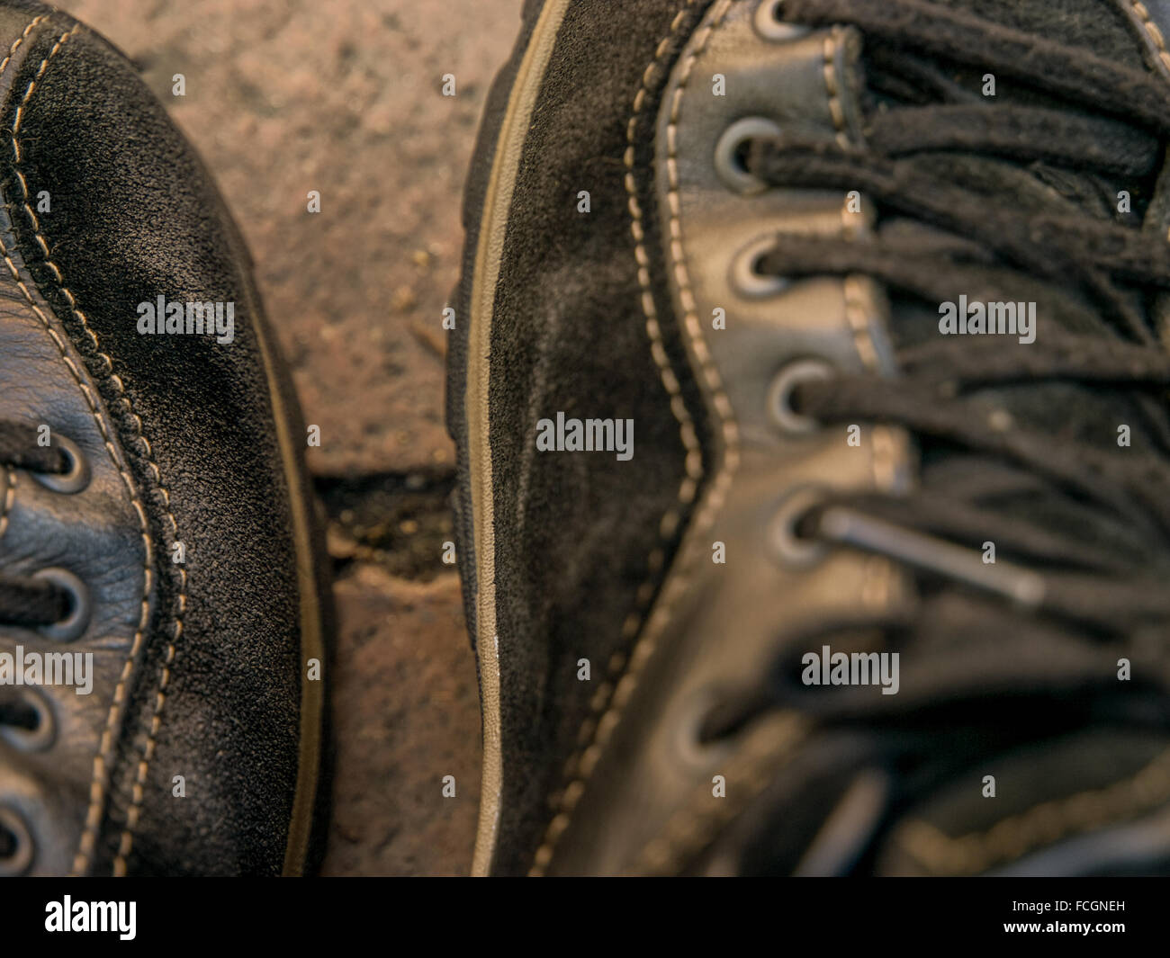 Tagliata di close-up di pelle nera e scarpe in pelle scamosciata con lacci sulla passerella di pietra. Foto Stock